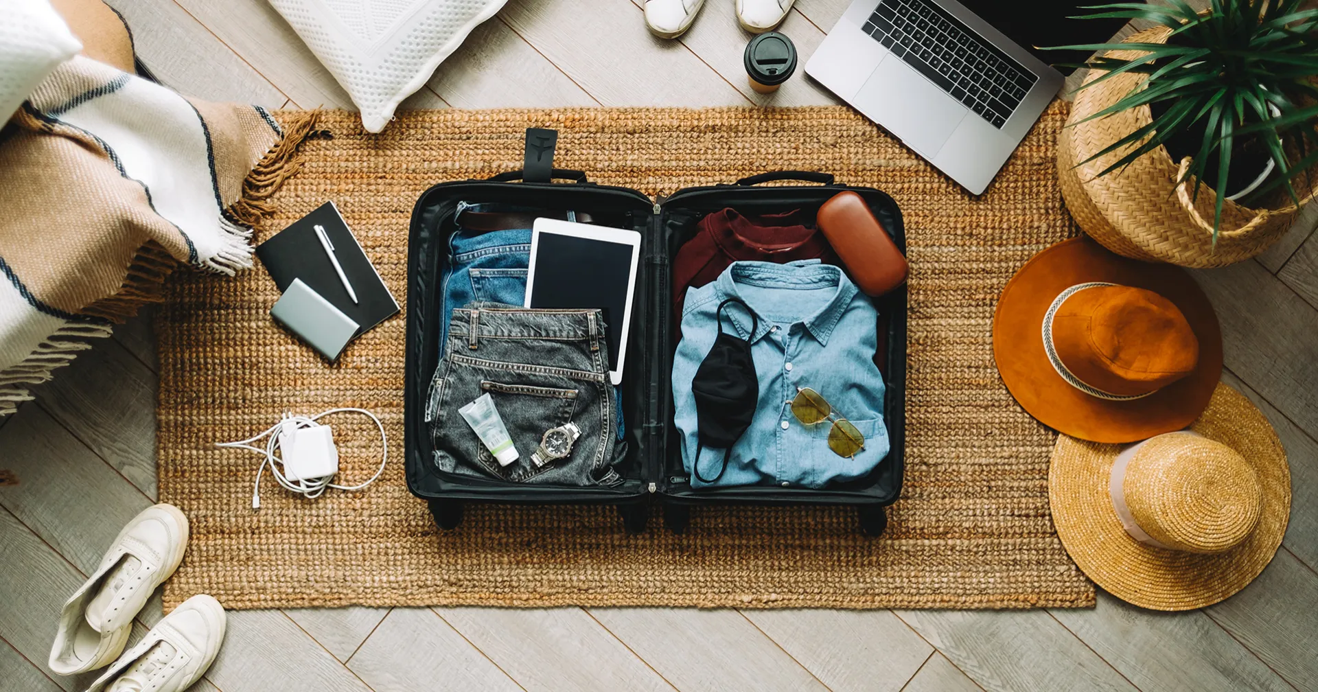 Campagne vakantiegevoel; koffer met kleding, schoenen, hoeden en digitale apparatuur uitgestald op de grond