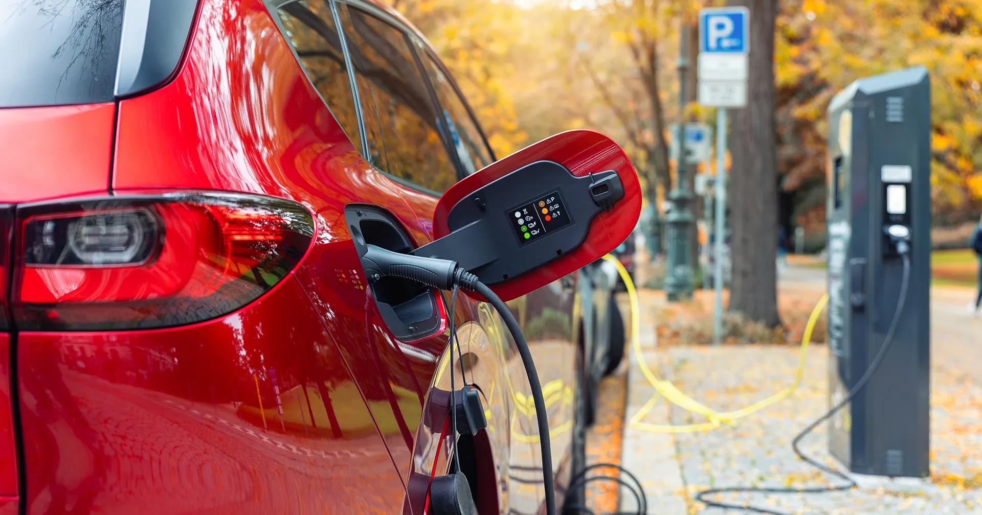 Rode SUV elektische plugin hybride staat geparkeerd bij een oplaadstation