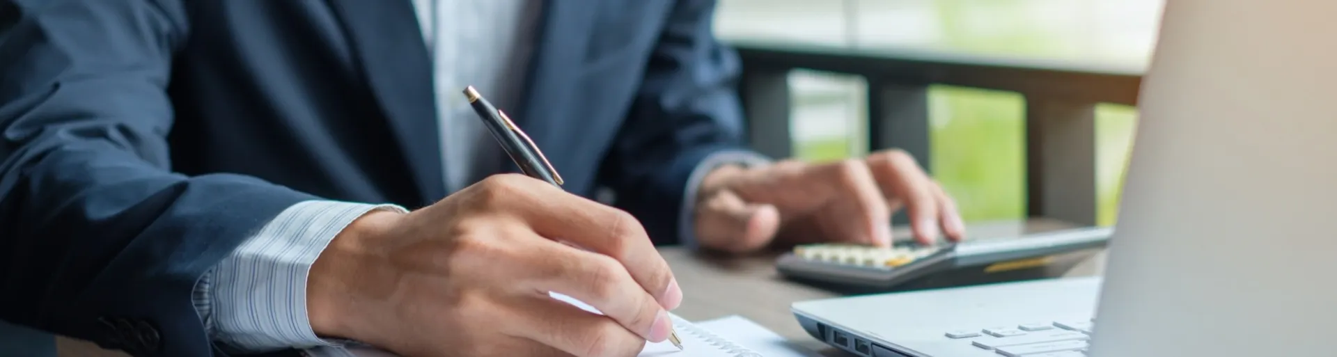 Man in pak maakt berekeningen op calculator en computer